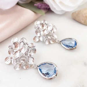 Peut inclure: Boucles d'oreilles en argent avec des grappes de fleurs et des accents de cristal bleu en forme de larme.