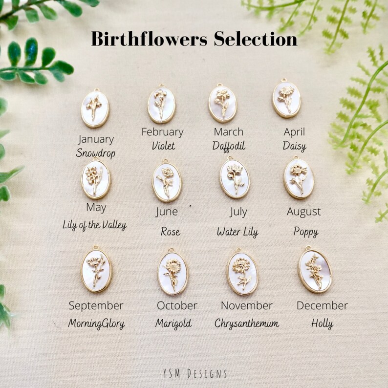 May include: A chart showing the birth flowers for each month of the year. The flowers are depicted as small, oval-shaped charms with gold accents. The charms are arranged in rows, with the month and flower name listed below each charm.