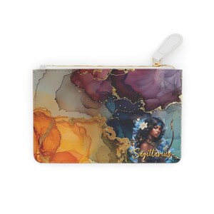 Pode incluir: Embreagem retangular com zíper dourado e puxador branco. O design apresenta um fundo abstrato em aquarela em tons de laranja, roxo e dourado, com uma ilustração de Sagitário e texto.