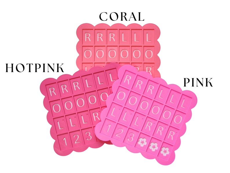May include: Three pink silicone molds with scalloped edges, each featuring letter and number cutouts. The molds are labeled "CORAL", "HOTPINK", and "PINK". The letters and numbers are in white.