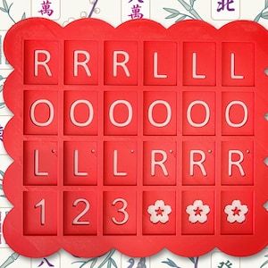 May include: A red, scalloped-edge tray with a grid of squares, each containing a white letter or number. The letters spell out "RRRLLLOOLLLRRR" and the numbers are "123". Three white flower symbols are also present.