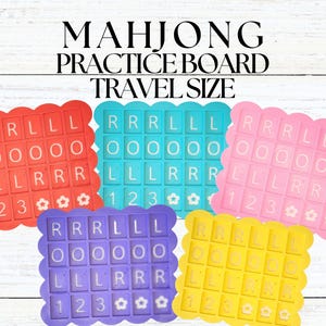 May include: Five brightly coloured Mahjong practice boards in red, teal, pink, purple, and yellow. Each board has a scalloped edge and features letter and number tiles for practice. The text "MAHJONG PRACTICE BOARD TRAVEL SIZE" is at the top.