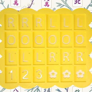 May include: A yellow tray with a scalloped edge holds 25 tiles. The tiles are yellow with white letters and numbers. The letters are R, L, and O. The numbers are 1, 2, and 3. There are also three flower-shaped tiles.