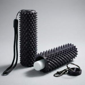 May include: Black cylindrical containers with a spiky texture, a wrist strap, and a keychain. One container is upright, the other is horizontal, revealing a white object inside. The items are on a grey surface.