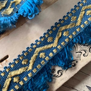 May include: Blue and gold trim with a geometric pattern and a fringed edge.