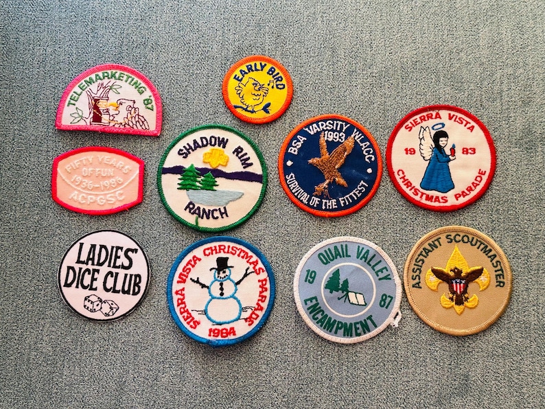 Op de afbeelding: Een verzameling vintage geborduurde patches met diverse ontwerpen en tekst. Patches zijn onder meer "Telemarketing '87", "Early Bird", "Shadow Rim Ranch", "BSA Varsity 1993", "Sierra Vista Christmas Parade" en "Ladies Dice Club".