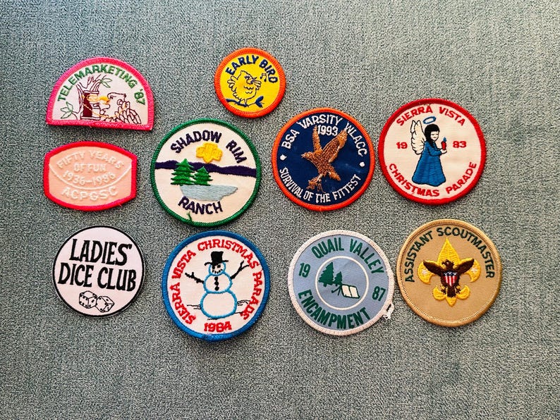 Op de afbeelding: Een verzameling vintage geborduurde patches met diverse ontwerpen en tekst. Patches zijn onder meer "Telemarketing '87", "Early Bird", "Shadow Rim Ranch", "BSA Varsity 1993", "Sierra Vista Christmas Parade" en "Ladies Dice Club".