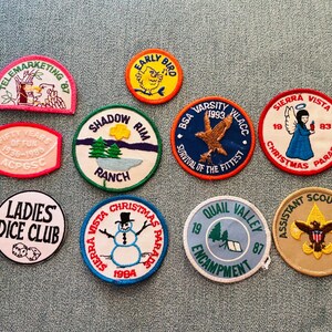 Op de afbeelding: Een verzameling geborduurde patches met diverse ontwerpen en tekst. Patches zijn onder meer "Telemarketing '87", "Early Bird", "Shadow Rim Ranch", "BSA Varsity 1993", "Sierra Vista Christmas Parade", "Ladies Dice Club" en "Assistant Scoutmaster".