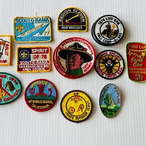 May include: A collection of vintage scout patches in various shapes and colors. Patches include text like "Scout-O-Rama", "Mission Peak", and "Jamboree". Designs feature camping scenes, animals, and text.