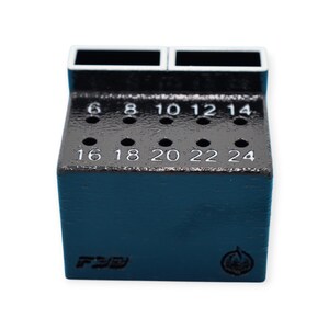 May include: A dark blue tool holder with multiple holes and numbered markings. The top section has two rectangular openings. Numbers 6 through 24 are visible, indicating sizes. The base has Japanese text and a logo.