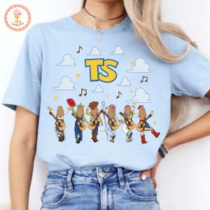 May include: A light blue t-shirt featuring a graphic print of six figures with long hair, each holding an acoustic guitar. The design includes white clouds, yellow stars, brown musical notes, and the large yellow text TS centered at the top.