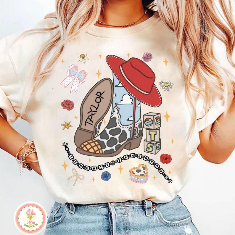 May include: A cream-coloured t-shirt featuring a graphic of a cowboy boot with a cow print pattern, a red cowboy hat, and the name Taylor. The design includes blocks with the letters T, S, and the number 13, plus a beaded string with the text I KNEW YOU.