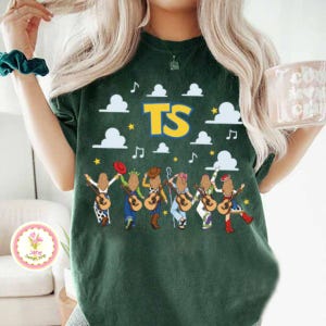 May include: A dark green short-sleeve t-shirt featuring a graphic print of six figures with long blonde hair holding acoustic guitars. The design includes white clouds, yellow stars, musical notes, and the large yellow text TS in a bold font.
