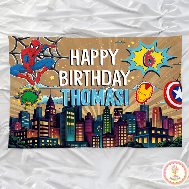 May include: A colorful birthday banner featuring the text "HAPPY BIRTHDAY THOMAS!" with a cityscape backdrop. Includes illustrations of Spider-Man, the Hulk's fist, Iron Man's helmet, and Captain America's shield. A large number 6 is also displayed.