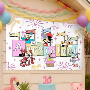 May include: A rectangular party banner featuring the text Auroraland in colorful block letters. The design includes illustrations of Mickey Mouse, Minnie Mouse, Donald Duck, Daisy Duck, Goofy, and Pluto wearing party hats, surrounded by fireworks.