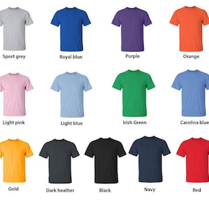 Op de afbeelding: Een verzameling t-shirts met korte mouwen in verschillende kleuren, waaronder sportgrijs, koningsblauw, paars en oranje. Andere kleuren zijn lichtroze, lichtblauw, Iers groen, Carolina blauw, goud, donkergrijs, zwart, marineblauw en rood.