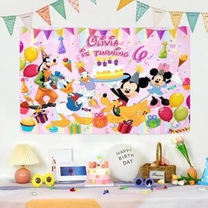 Puede incluir: Una pancarta rosa de cumplea&ntilde;os con personajes de Disney como Mickey Mouse, Minnie Mouse, Donald Duck y Goofy. La pancarta dice "Olivia cumple 6 a&ntilde;os" e incluye globos, regalos y una tarta. Las decoraciones de la fiesta est&aacute;n dispuestas sobre una mesa.