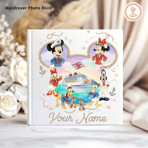 May include: A white hardcover photo book featuring Mickey Mouse, Minnie Mouse, Donald Duck, Goofy, and Chip and Dale. The cover has a nautical theme with a cruise ship and the text "Your Name" in gold script. The words "Hardcover Photo Book" are at the top.
