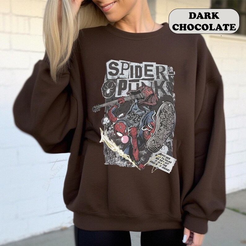 Peut inclure: Sweat-shirt marron chocolat fonc&eacute; avec un motif Spider-Punk. Le motif comprend des personnages de Spider-Man, le texte "SPIDER PUNK" et des &eacute;l&eacute;ments de style bande dessin&eacute;e. Le sweat-shirt a des manches longues et un col rond.