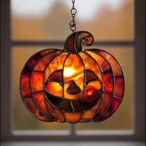 May include: A decorative stained glass pumpkin lantern, ideal for Halloween. The pumpkin features a smiling face and is made of orange, red, and brown glass. It hangs from a chain and emits a warm, inviting glow.
