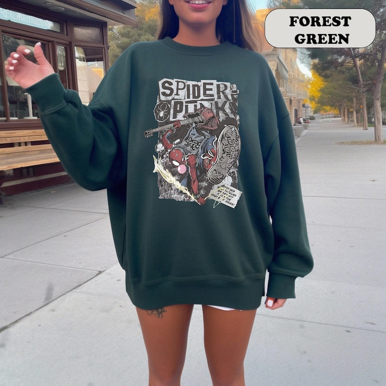 Peut inclure: Sweat-shirt vert for&ecirc;t avec un motif de Spider-Man de style bande dessin&eacute;e et le texte "SPIDER PUNK". Le motif utilise du rouge, du bleu et du blanc. Le sweat-shirt est de couleur unie et a des manches longues.