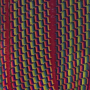 Peut inclure: Un rideau ou tenture murale au crochet fait main et vibrant. Le motif pr&eacute;sente un motif r&eacute;p&eacute;titif de blocs color&eacute;s aux teintes arc-en-ciel, avec une bordure rouge audacieuse et des franges. La pi&egrave;ce est probablement fabriqu&eacute;e &agrave; partir de fil, mettant en valeur un attrait textur&eacute; et artistique.