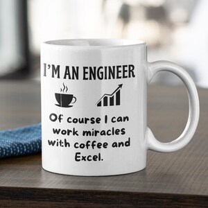 May include: White ceramic mug with the text "I'M AN ENGINEER" and the phrase "Of course I can work miracles with coffee and Excel." A coffee cup and a bar graph are also printed on the mug.