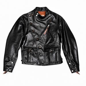 May include: Black leather jacket featuring an asymmetrical button design, multiple pockets, and a zipped chest pocket. The jacket has a classic biker style with a brown leather interior and buttoned cuffs.