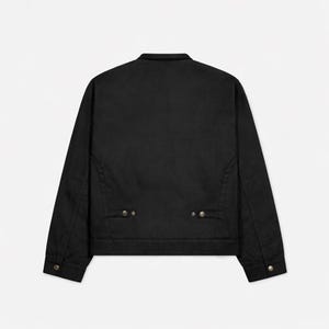 May include: A black jacket with a collar and long sleeves. The jacket has two small pockets near the waist and button closures on the cuffs. The back of the jacket is plain and the fabric appears to be a sturdy material.