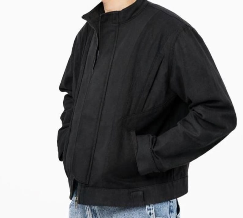 May include: Black jacket with a stand-up collar, front zipper, and side pockets. The jacket has a ribbed design on the front and a straight hem. The sleeves are long and the jacket is made of a durable material.