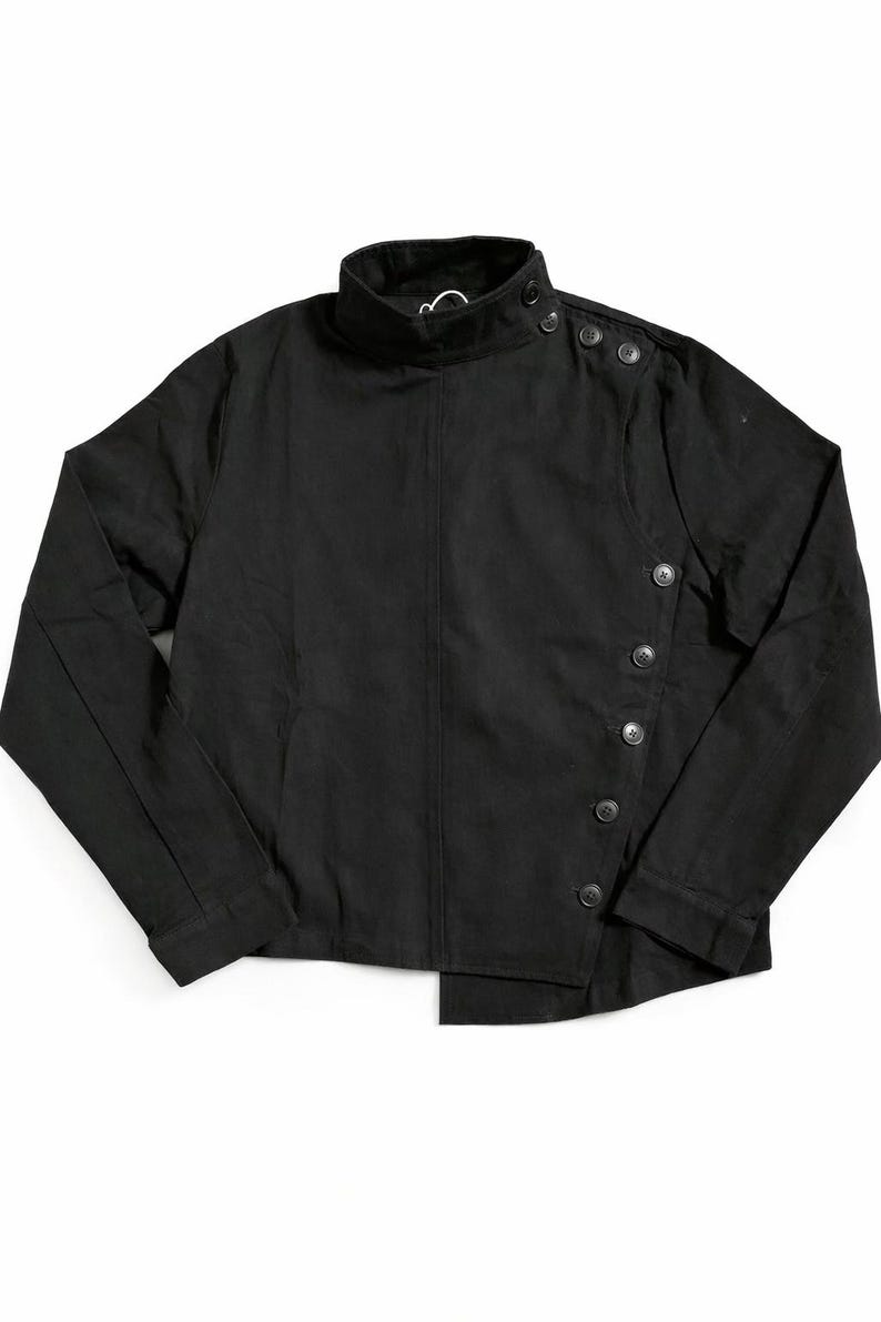 May include: Black jacket with a high collar and asymmetrical button closure. The jacket features a series of buttons down the front and on the shoulder. The garment is made of a solid black fabric.