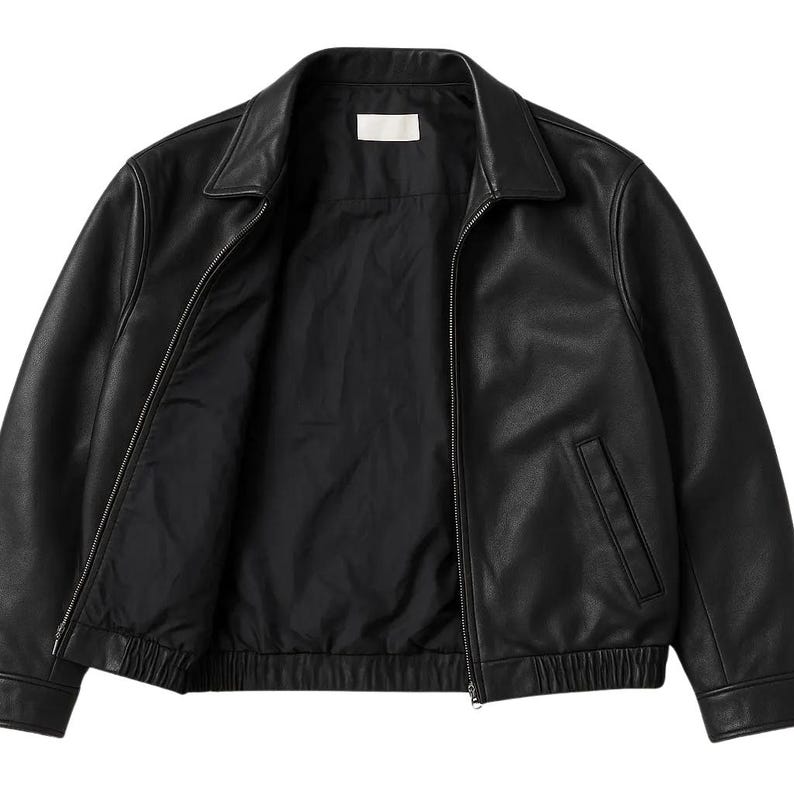May include: Black leather jacket with a collared neckline and a zipper closure. The jacket has two front pockets and a ribbed hem. The interior lining is black. A classic outerwear piece.
