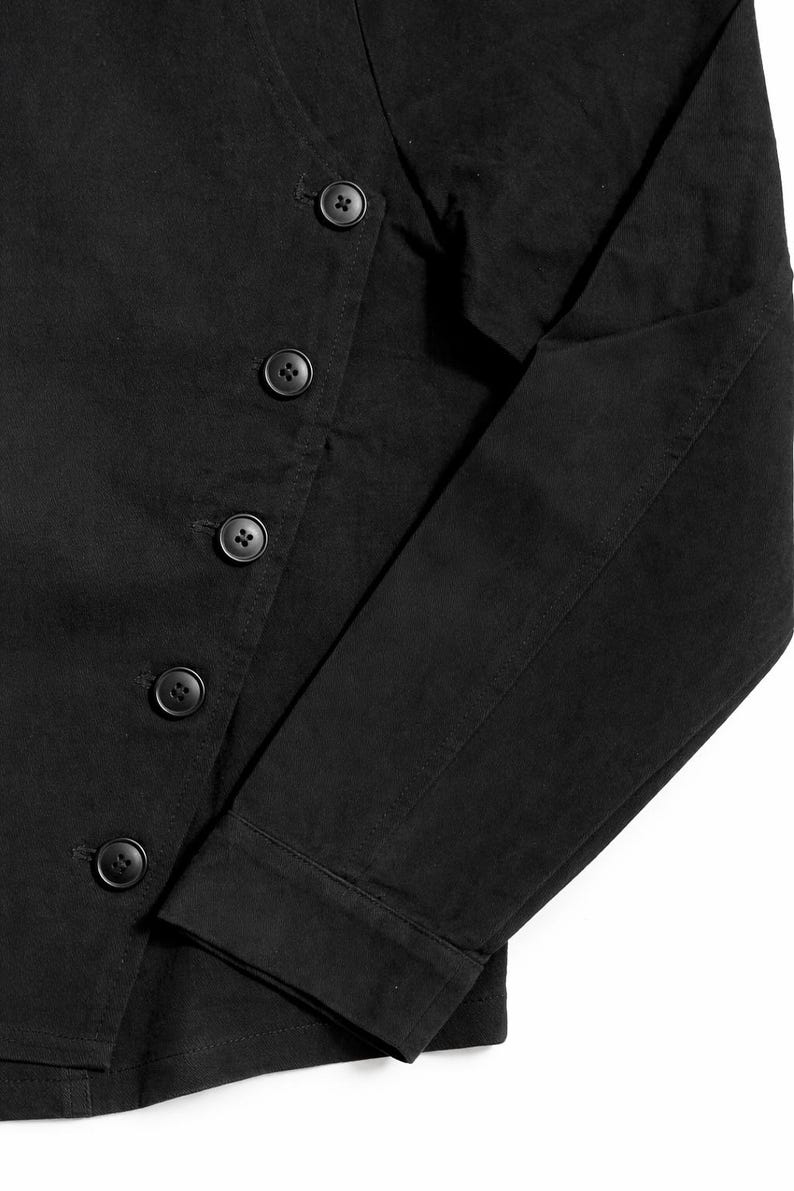 May include: Black jacket with a button-up closure and long sleeves. The jacket features a series of round, black buttons down the front and on the sleeves. The fabric appears to be a solid, dark color.