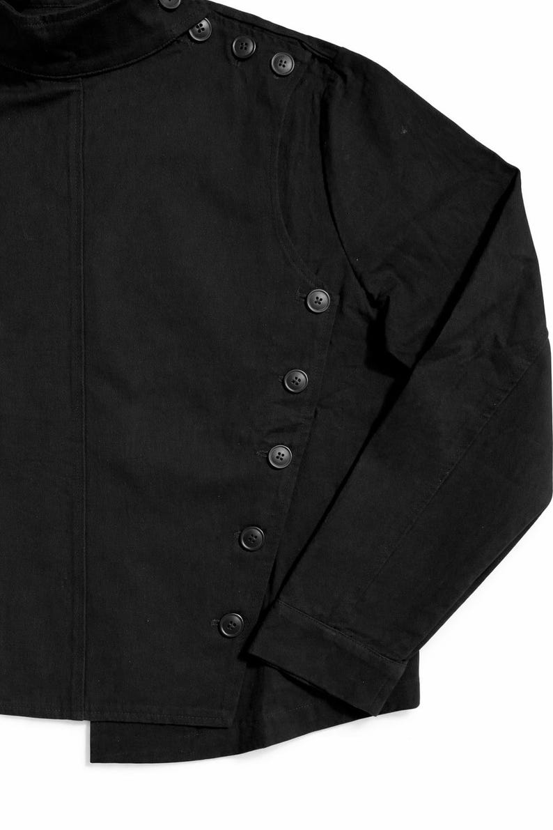 May include: Black long-sleeved shirt with a high collar and button details. The shirt features a series of buttons down the front and on the collar. The fabric appears to be a solid, dark color.