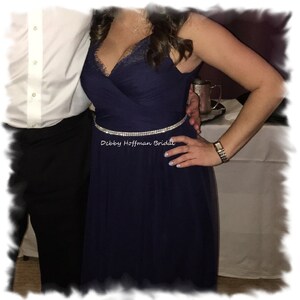 May include: A navy blue tulle dress with a lace bodice and a silver rhinestone belt. The text "Debby Hoffman Bridal" is visible on the belt.