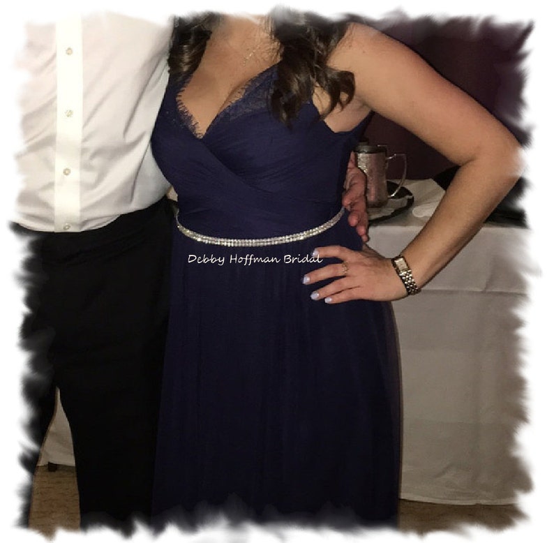 May include: A navy blue tulle dress with a lace bodice and a silver rhinestone belt. The text "Debby Hoffman Bridal" is visible on the belt.