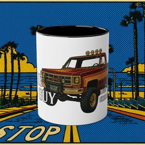 Puede incluir: Taza de cerámica blanca con interior negro, con una ilustración retro de una camioneta GMC roja y naranja. La taza tiene el texto "THE GUY" y "FALLGUY" en la parte delantera, con un diseño de fondo costero.
