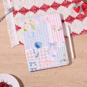 May include: A decorative tablet case featuring a patchwork design with floral and bow illustrations in pastel pink and blue. The case includes images of flowers, hearts, and a champagne bottle.