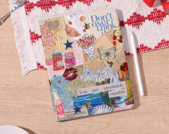 May include: A colorful journal with a collage design featuring illustrations of flowers, a croissant, a butterfly, and the text "Don't overthink." The journal also includes the text "You are absolutely capable."