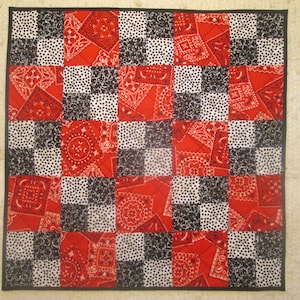 May include: A red and black checkered quilt with a bandana print. The quilt is made up of 36 squares, each with a different bandana pattern.