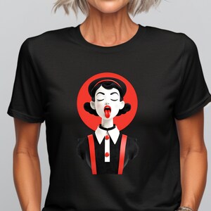 Può includere: T-shirt nero con un'illustrazione stilizzata di una donna con la lingua di fuori, su un cerchio rosso. La donna indossa un abito nero con bretelle rosse e un colletto bianco con bottoni rossi. Design audace e grafico.