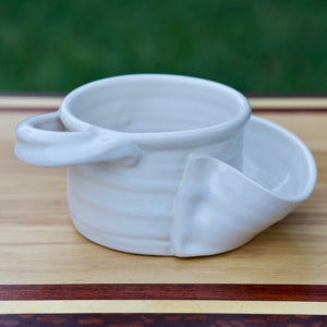 May include: White ceramic bowl with a handle and a separate dipping dish. The bowl has a textured, wavy design.