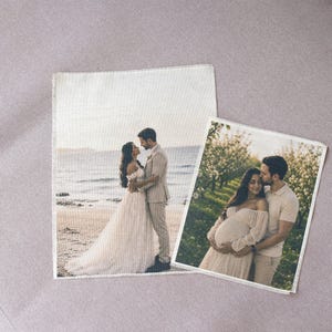 May include: Two square fabric prints featuring photographic images. The larger print shows a couple on a beach, while the smaller print displays a couple in a garden setting. Both prints have visible fabric textures and frayed edges.