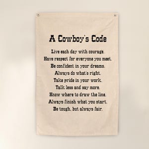 May include: A beige fabric wall hanging featuring the text "A Cowboy's Code" in black. The code includes inspirational phrases such as "Live each day with courage" and "Be tough, but always fair."