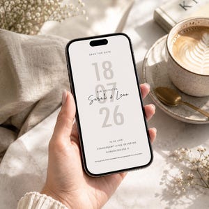 May include: A smartphone displaying a digital save the date announcement with the text SAVE THE DATE, 18 07 26, WIR HEIRATEN, Sarah & Leon, 15:00 UHR, STANDESAMT HAUS SEVERING, DURENSTRASSE 11, and a sentence about sharing the special moment.