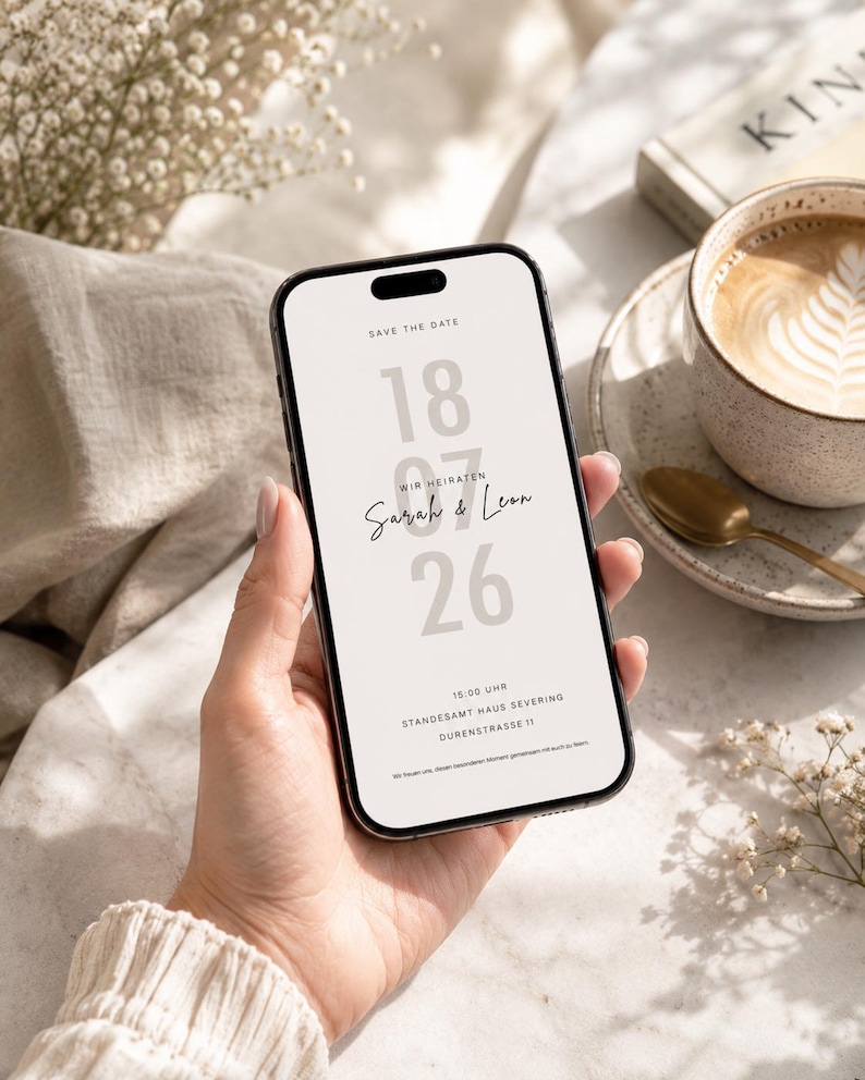 May include: A smartphone displaying a digital save the date announcement with the text SAVE THE DATE, 18 07 26, WIR HEIRATEN, Sarah & Leon, 15:00 UHR, STANDESAMT HAUS SEVERING, DURENSTRASSE 11, and a sentence about sharing the special moment.