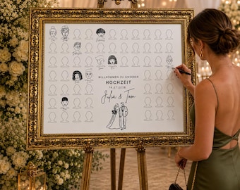 May include: A framed wedding guest sign with a gold ornate frame. The white sign has illustrated faces and the words "WILLKOMMEN ZU UNSERER HOCHZEIT 14.07.2026 Julia & Tom". A person is signing the guest book with a black pen.