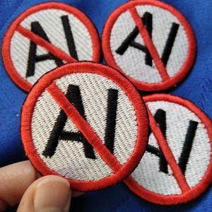May include: Four circular patches with a white background, black letters "AI" crossed out by a red diagonal line, and a red border. The patches are embroidered with a textured appearance.