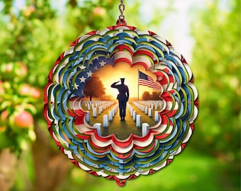 May include: A layered, circular ornament with a patriotic theme. The design features a soldier saluting in front of a cemetery with an American flag. The outer layers are red, white, and blue, creating a 3D effect. The ornament hangs from a silver chain.