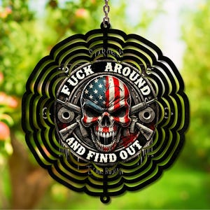 Può includere: Decorazione decorativa in metallo nero con un design a teschio. Il teschio presenta i colori della bandiera americana ed è circondato dal testo "FUCK AROUND AND FIND OUT" e da due fucili incrociati. Il design è stratificato con un bordo smerlato.